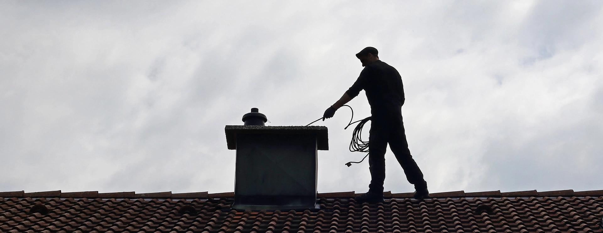 kominiarz czyszczący komin na dachu